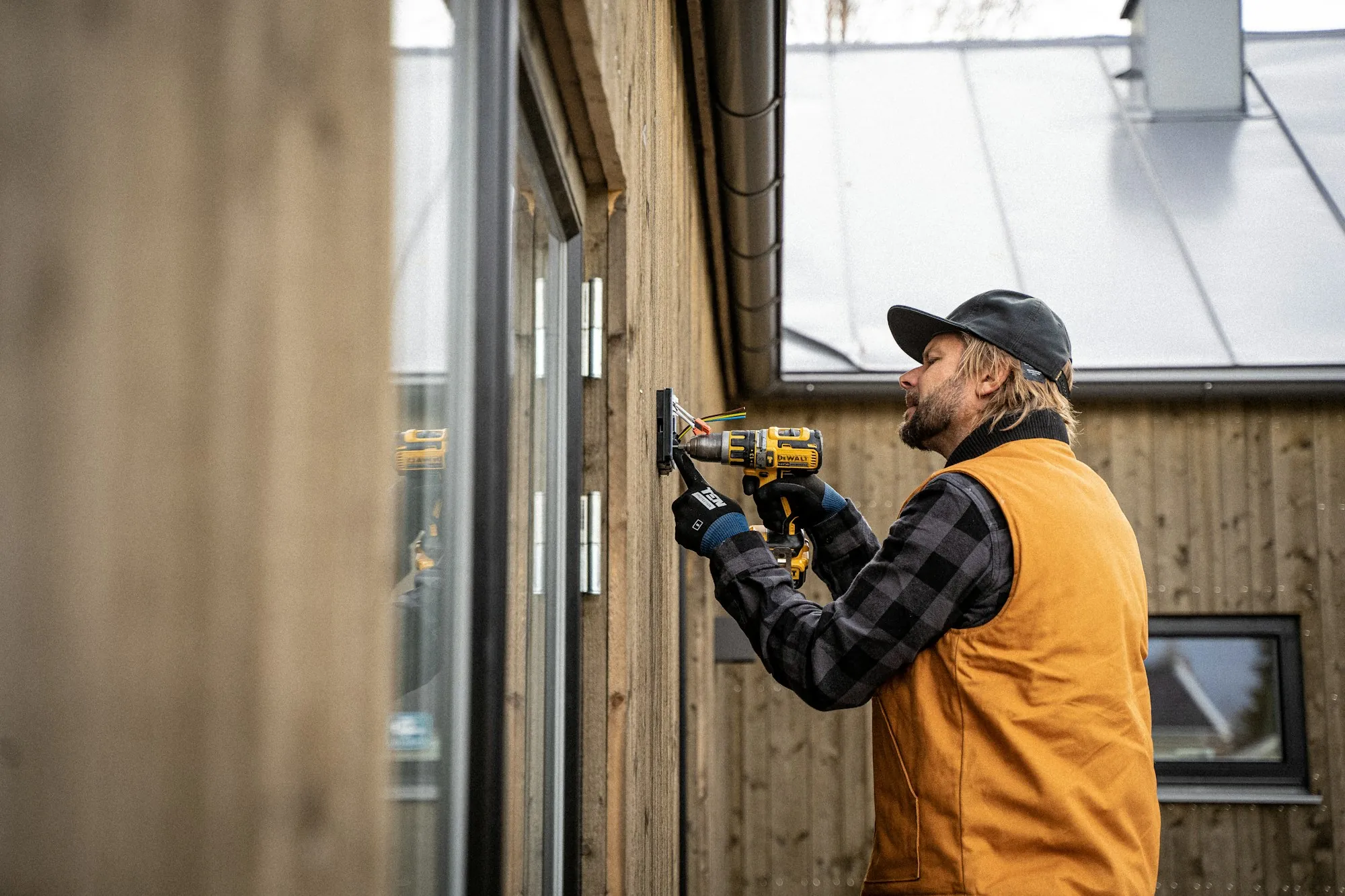 Electrician drilling into a wall on a job
