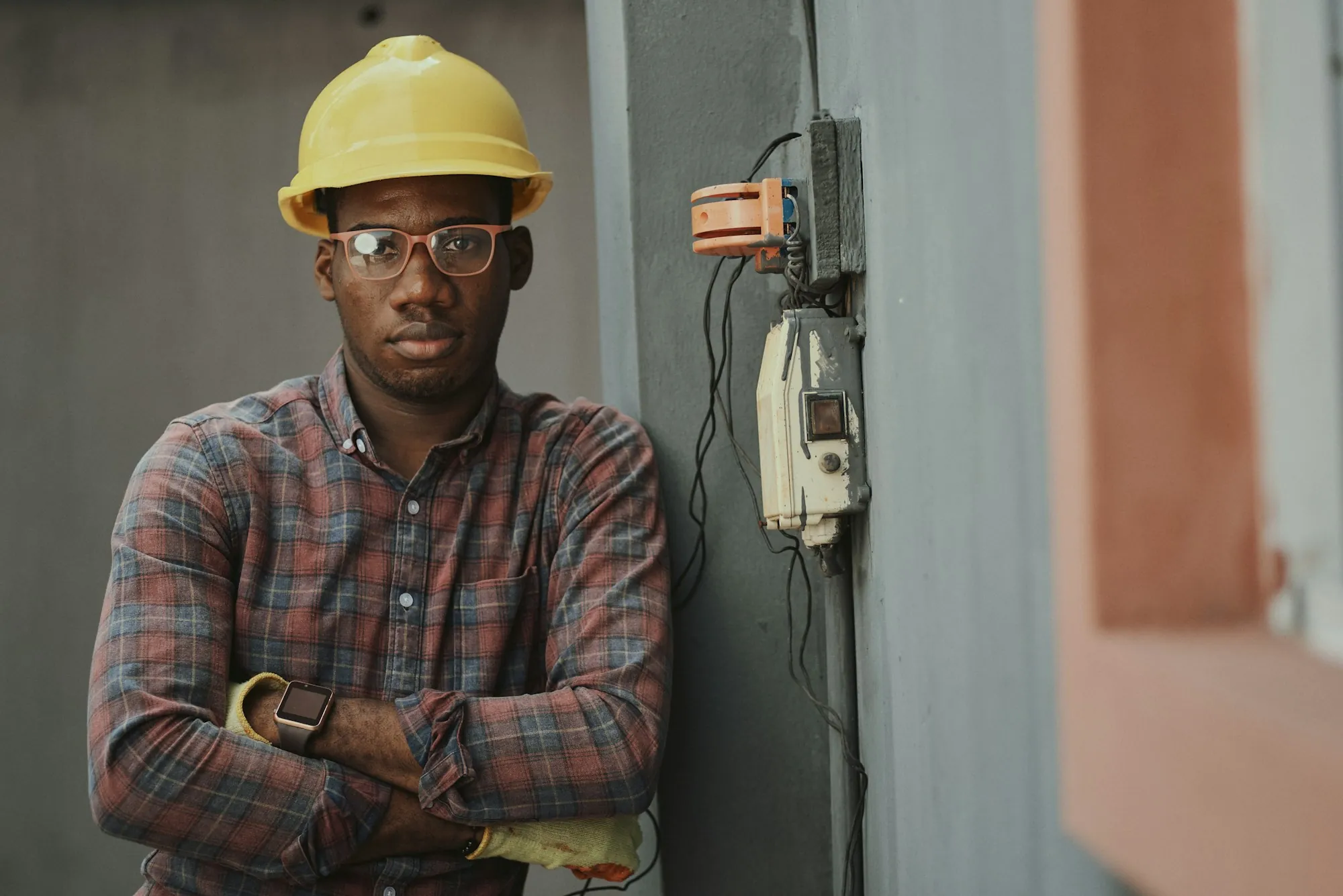 Electrician in a hard hat beside a home service panel