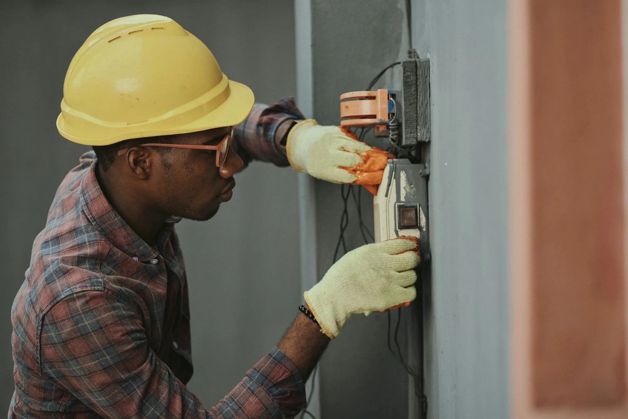 Electrician in a hard hat working on a home electrical panel